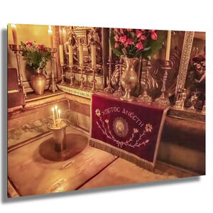 Może przedstawiać: Zbliżenie na złoty ołtarz z czerwonym aksamitnym obrusem wyszytym słowami "ΧΡΙΣΤΟΣ ΑΝΕΣΤΗ" (Chrystus zmartwychwstał) w języku greckim. Ołtarz jest ozdobiony świecami, kwiatami i innymi przedmiotami religijnymi.