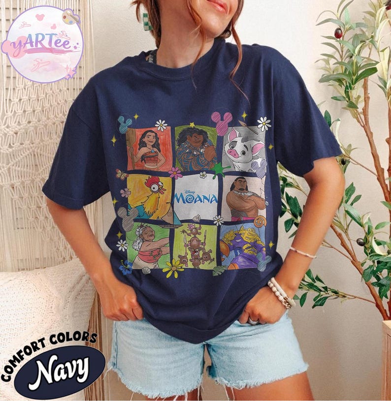 May include: Navy blue t-shirt featuring a grid of Moana characters. The shirt includes images of Moana, Maui, Pua, Hei Hei, and others. The word "Moana" is printed in the center. The shirt also has the words "Comfort Colors Navy" printed on the bottom.