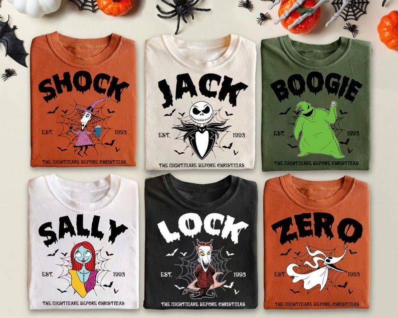 May include: Six t-shirts with crew necks featuring characters from "The Nightmare Before Christmas." The shirts are in various colors: orange, cream, and green. Each shirt has a character's name in large black letters, with graphics and the text "EST. 1993."