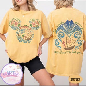 May include: Yellow t-shirt with a front graphic featuring a Mickey Mouse head design with floral and boat motifs, and text that reads "COME WHAT MAY" and "KNOW THE WAY." The back of the shirt has a boat design and the text "There is nowhere you can go that I won't be with you..."