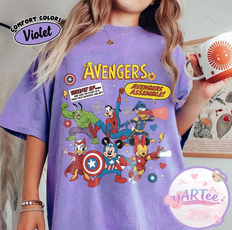 May include: A violet-colored t-shirt featuring a graphic of The Avengers characters, including Hulk, Spider-Man, and Mickey Mouse as Captain America. The shirt has the text "The Avengers" and "Avengers Assemble!" printed on it. The shirt also has the text "Comfort Colors" and "Violet" printed on it.