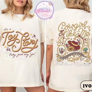 May include: An ivory t-shirt featuring a front graphic with the text "it's a Toy Story" in a rope-style font and "Baby, just say "yes"" below. The back graphic displays "Cowgirl Like Me" with a cowboy hat, lasso, and desert imagery.