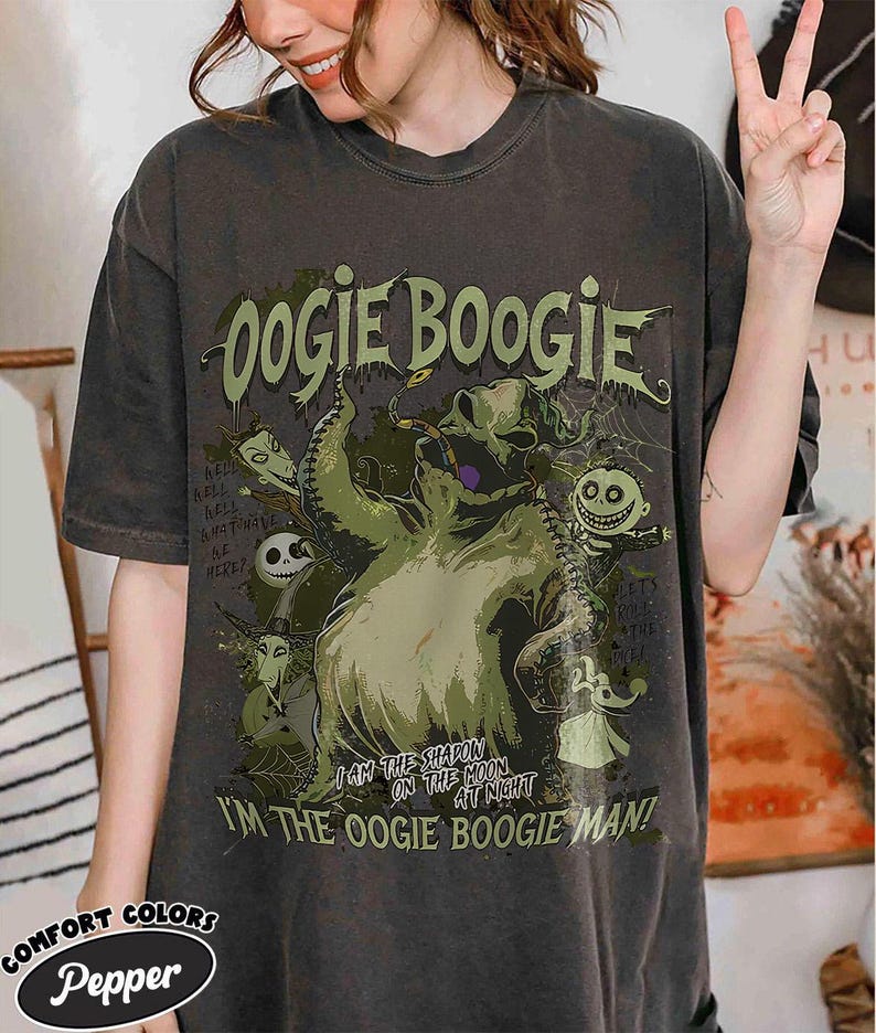 Puede incluir: Camiseta gris oscuro con la inscripci&oacute;n "Oogie Boogie" en verde y un dibujo del personaje de The Nightmare Before Christmas. La camiseta tambi&eacute;n incluye las frases "I am the shapon on the moon at night" y "I'm the Oogie Boogie Man!"
