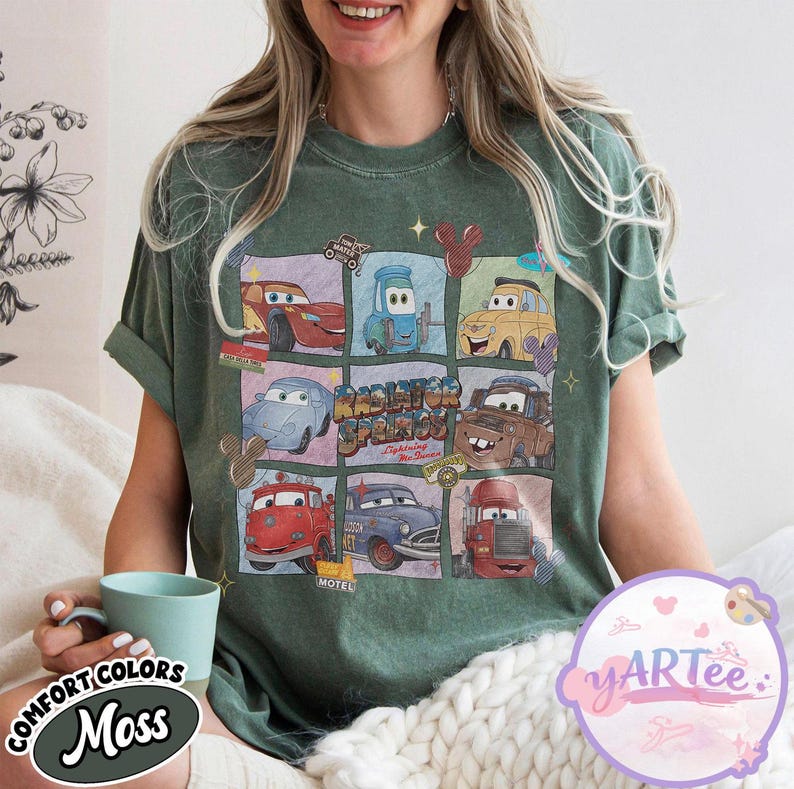 May include: Green t-shirt featuring a grid of cartoon cars from the movie Cars. The shirt has the text "Radiator Springs" and "Lightning McQueen". The shirt also has the text "Comfort Colors Moss" on the bottom left.