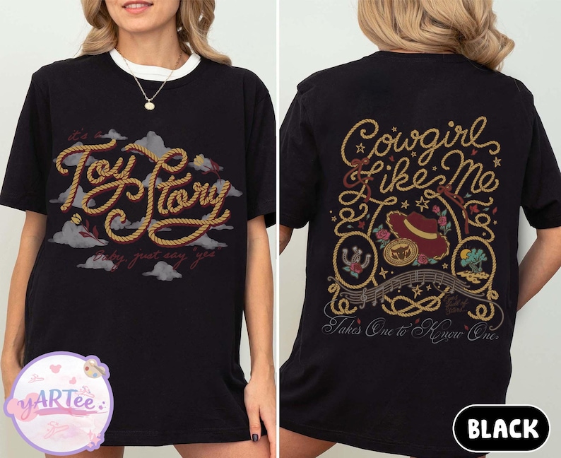 May include: A black t-shirt featuring a front graphic with the text Toy Story in a rope-style font against a background of clouds. The back graphic displays the text Cowgirl Like Me and Takes One to Know One with a cowboy hat and rope motifs.