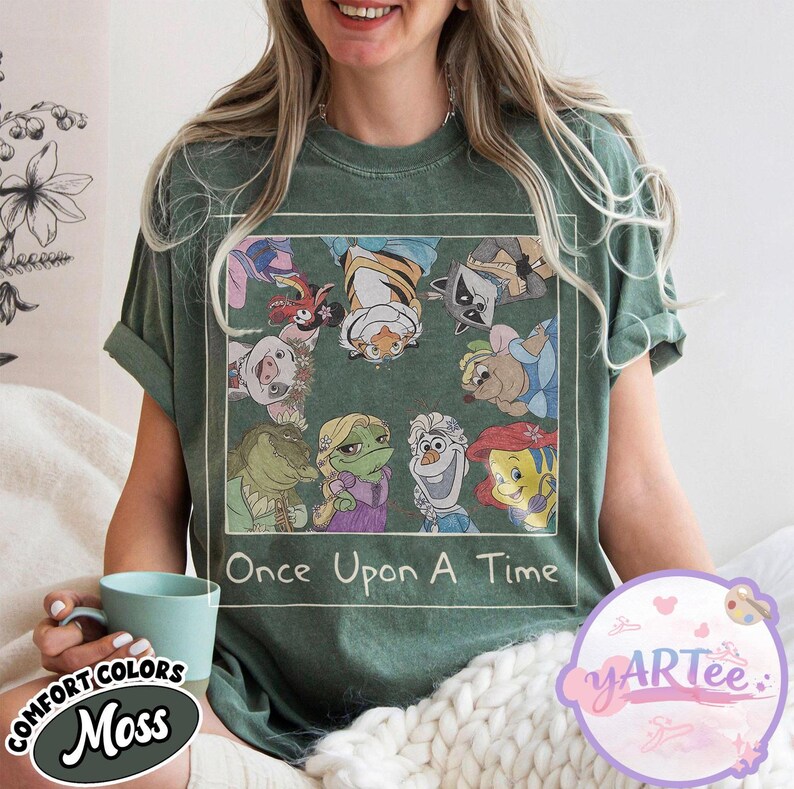 May include: Moss green t-shirt featuring a graphic of cartoon characters from various animated films. The graphic is framed with a white border and includes the text "Once Upon A Time". The shirt is made of a soft, comfortable material.