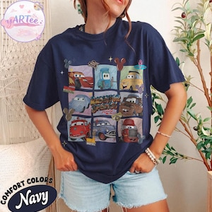 May include: Navy blue t-shirt featuring a grid of cartoon cars from the movie Cars. The shirt has the words "Radiator Springs" and "Lightning McQueen" printed on it. The shirt is made of a soft, comfortable material.