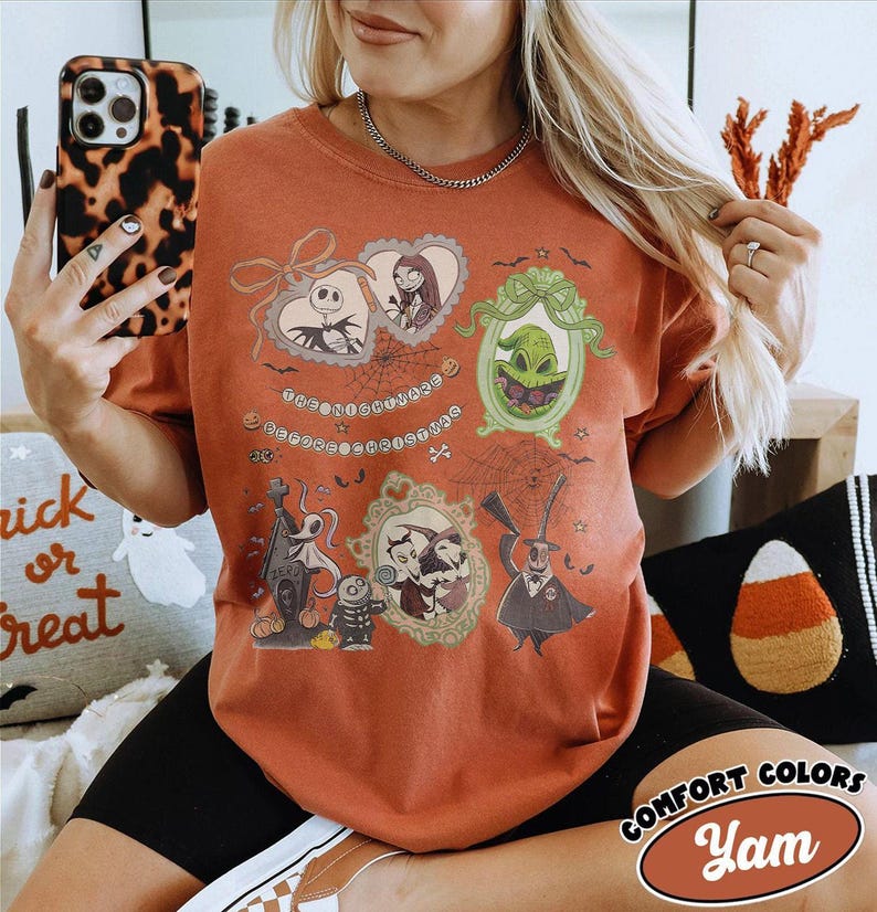 Puede incluir: Camiseta naranja quemado con ilustraciones enmarcadas de personajes de The Nightmare Before Christmas. La camiseta incluye a Jack Skellington, Sally, Oogie Boogie y otros personajes. El texto en la camiseta dice "The Nightmare Before Christmas".