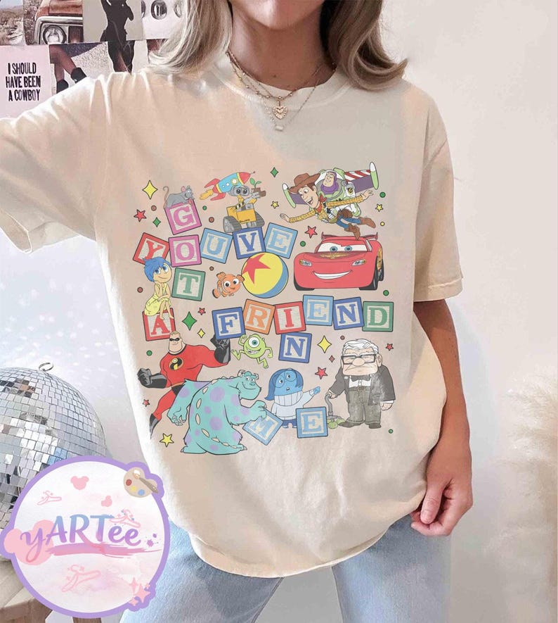 Puede incluir: Camiseta color crema con un gr&aacute;fico colorido de varios personajes animados y la frase "You've Got A Friend". El dise&ntilde;o incluye personajes de pel&iacute;culas de animaci&oacute;n populares, con un tema l&uacute;dico y nost&aacute;lgico.