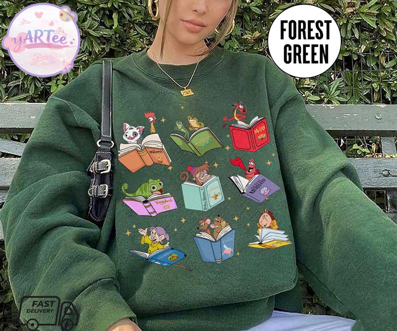 Puede incluir: Sudadera verde bosque con ilustraciones coloridas de personajes animados leyendo libros. La sudadera tiene cuello redondo y mangas largas. El texto "Forest Green" est&aacute; impreso en la parte superior derecha.
