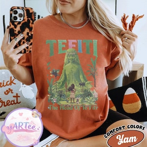 K&ouml;nnte beinhalten: Ein orangefarbenes T-Shirt mit einem Motiv von Te Fiti aus dem Film Moana. Das Design enth&auml;lt das Wort "TE FITI" in Gr&uuml;n und Blau sowie den Satz "The Head Of Te Fiti". Das Shirt geh&ouml;rt zur Comfort Colors Kollektion.