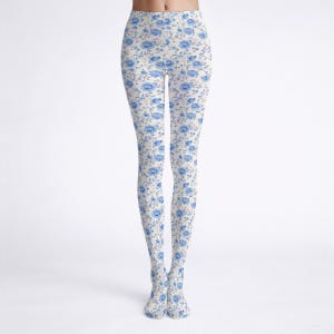May include: Floral patterned leggings. The leggings have a cream-coloured base, adorned with a repeating design of blue flowers and green stems. These leggings are made from a soft, stretchy fabric.