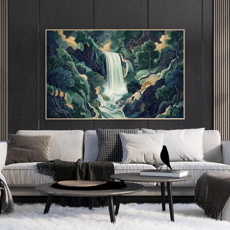 Large framed Japanese waterfall wall art displayed above a modern beige sofa, featuring a dramatic vertical white waterfall flowing through deep navy canyon cliffs and emerald green foliage, styled in a contemporary living room with dark paneled walls and a minimalist coffee table.