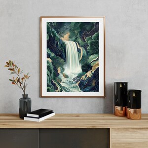 Framed Japanese waterfall art print displayed above a wooden console table, featuring a vertical cascading white waterfall through deep blue canyon cliffs and lush green foliage, styled with a ceramic vase, dried branches, stacked books, and small decor objects against a light neutral wall.