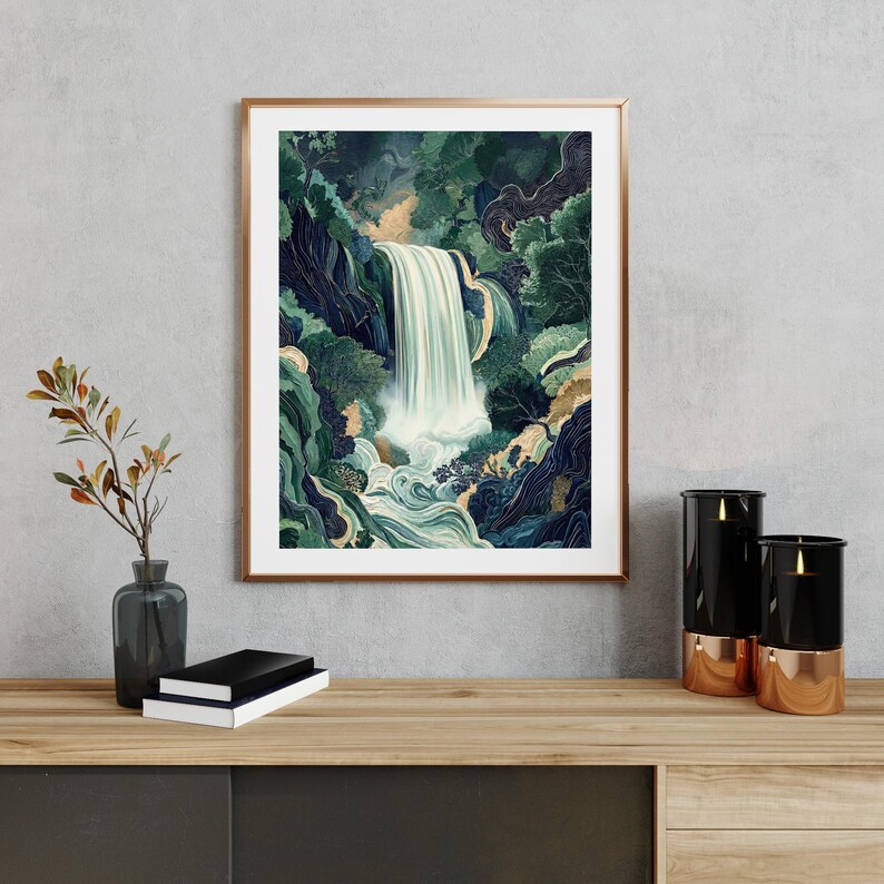 Framed Japanese waterfall art print displayed above a wooden console table, featuring a vertical cascading white waterfall through deep blue canyon cliffs and lush green foliage, styled with a ceramic vase, dried branches, stacked books, and small decor objects against a light neutral wall.