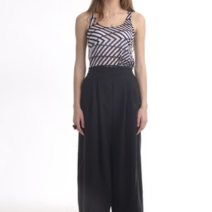 May include: A sleeveless tank top featuring a black and white geometric diagonal stripe pattern paired with solid black high-waisted wide-leg trousers. The outfit is completed with black woven slip-on shoes. The ArtAffect logo is in the top left.