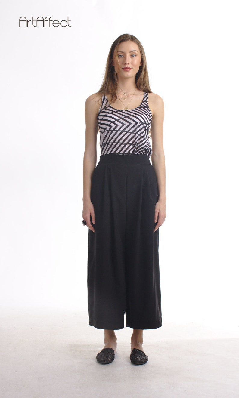 May include: A sleeveless tank top featuring a black and white geometric diagonal stripe pattern paired with solid black high-waisted wide-leg trousers. The outfit is completed with black woven slip-on shoes. The ArtAffect logo is in the top left.