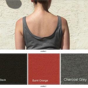 Pu&ograve; includere: Una canotta grigio antracite con scollo rotondo vista da dietro. Sotto la canotta ci sono tre campioni di tessuto quadrati etichettati Black, Burnt Orange e Charcoal Grey, che rappresentano le opzioni di colore disponibili per questo capo.