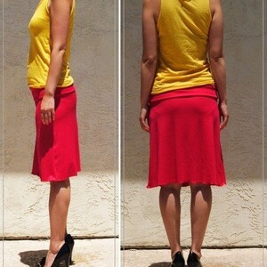 May include: A bright yellow sleeveless tank top paired with a knee-length red skirt. The skirt features a wide, flat waistband and a slightly flared hemline. The outfit is completed with black high-heeled shoes, visible from both side and back views.