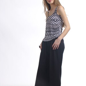May include: A sleeveless tank top featuring a black and white geometric chevron pattern paired with solid black wide-leg cropped trousers and black woven slip-on shoes. The top has a scoop neckline and the trousers have a loose, flowing fit.