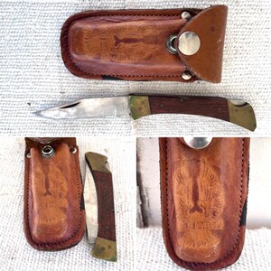 May include: A brown leather sheath with a metal snap closure and an eagle design. A folding pocket knife with a wooden handle and a stainless steel blade is in the sheath.