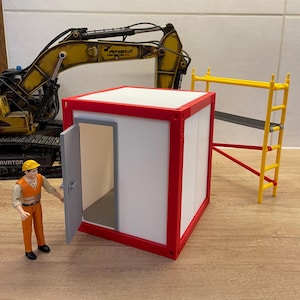 Op de afbeelding: Een miniatuur bouwplaats met een wit en rode container, een open deur, een geel en rood steiger en een gele graafmachine. Een bouwvakker figuur staat bij de container, wat bijdraagt aan de realistische details van de scène.