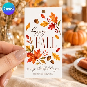 May include: A rectangular white gift tag featuring a watercolor illustration of autumn leaves, red berries, and brown acorns. The text reads "happy FALL" in a mix of script and serif fonts, followed by "so very thankful for you" and "from the Rowans".