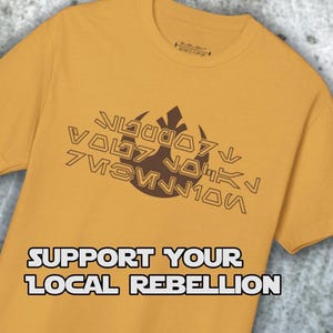 May include: A yellow t-shirt with a brown rebel alliance symbol and the text "SUPPORT YOUR LOCAL REBELLION".