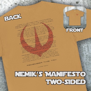 May include: Mustard-colored two-sided t-shirt with the text "NEMIK'S MANIFESTO TWO-SIDED". The back of the shirt features a red graphic and text. The front has a small red symbol. The shirt is made of a soft material.