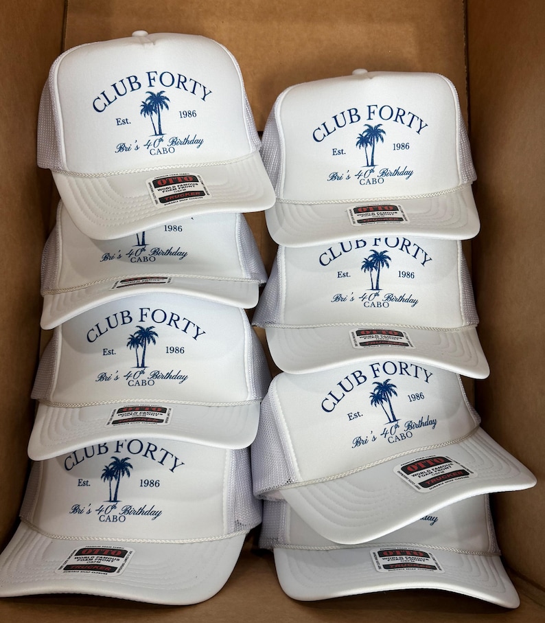 May include: A stack of white trucker hats with a blue palm tree graphic and the text "CLUB FORTY Est. 1986 Bri's 40th Birthday CABO". The hats have a mesh back and a curved brim.
