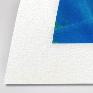 The image is a close-up of a white paper with a blue and green abstract shape or design on it.