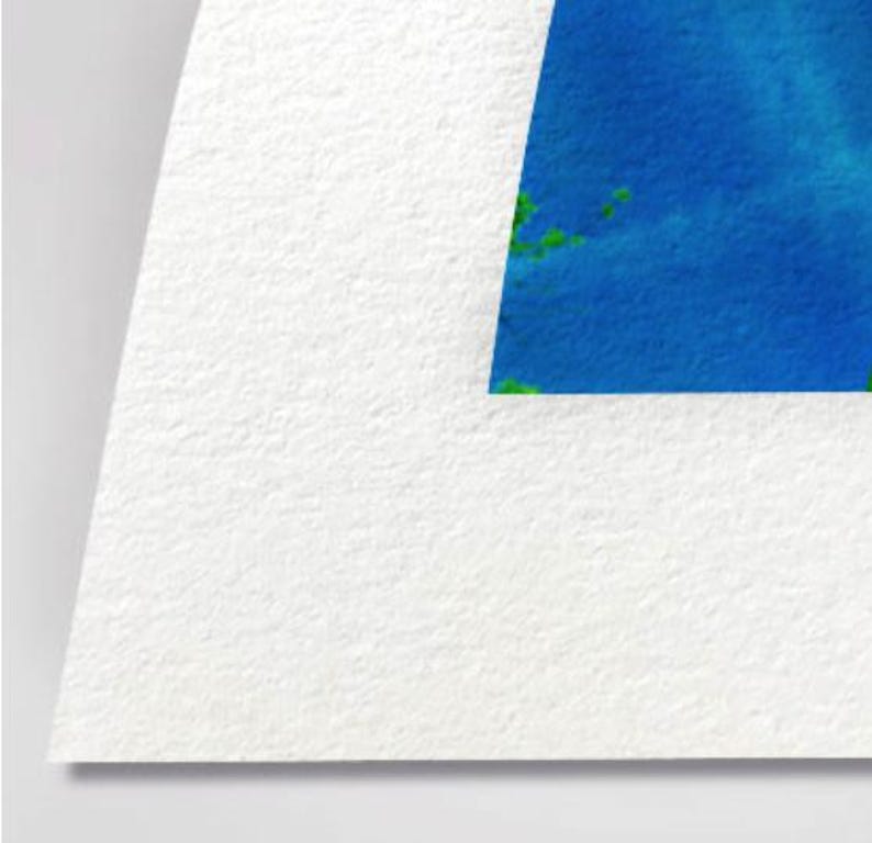 The image is a close-up of a white paper with a blue and green abstract shape or design on it.