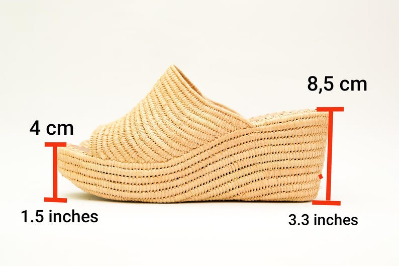 May include: A woven raffia wedge sandal in a natural beige color. The sandal has an open toe design and a wedge heel that measures 3.3 inches (8.5 cm) high. The platform is 1.5 inches (4 cm) high. The sandal is a slip-on style.