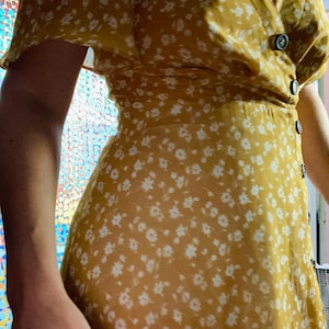 2010s does 1930s tumeric color all polyester chiffon dress with decorative front buttons, back zipper closure.