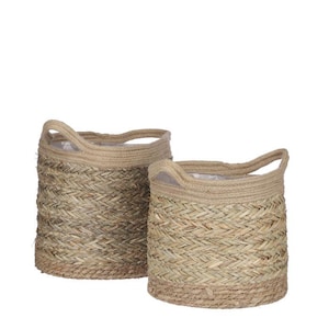 May include: Two woven baskets with handles. The baskets are made of natural-coloured woven material with a light brown trim and handles. The baskets are round and have a cylindrical shape. The baskets are likely used for storage or decoration.