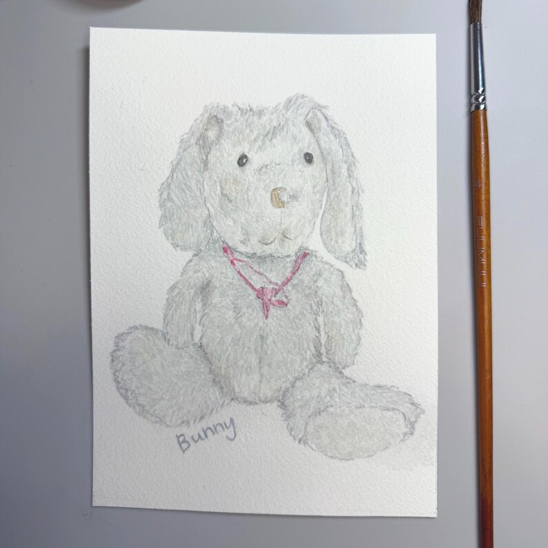 May include: Watercolor painting of a gray bunny with long ears and a pink ribbon around its neck. The word "Bunny" is written in cursive at the bottom. The bunny is sitting on a white background.