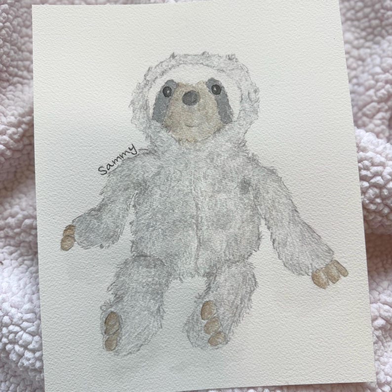 May include: Watercolor painting of a gray sloth wearing a hooded outfit. The sloth has a light brown face and paws, with the name "Sammy" written in cursive on the left side. The artwork is on white paper.