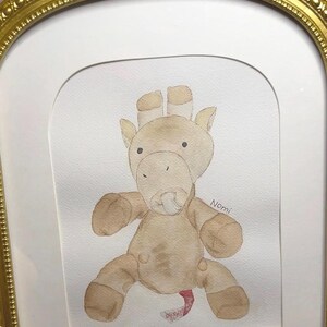 May include: Watercolor painting of a tan giraffe plush toy with a pacifier, framed in a gold ornate frame. The giraffe has brown accents and is sitting. The name "Nomi" is written on the right side of the painting.