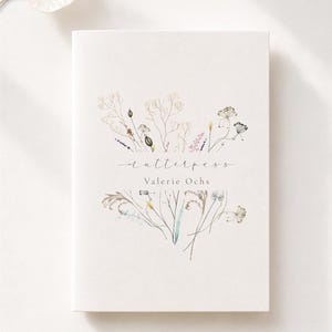 Könnte beinhalten: Ein weißes, rechteckiges Heft mit einer zarten Aquarellillustration von Wildblumen und Gräsern. Der Text "mutterpass" ist in Schreibschrift über dem Namen "Valerie Ochs" in einer klaren, serifenlosen Schrift mittig auf dem Einband gedruckt.