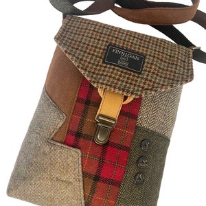 May include: A brown, green, and red patchwork crossbody bag with a flap closure and a metal buckle. The bag has a brown leather strap and a label that reads "Finnegan".