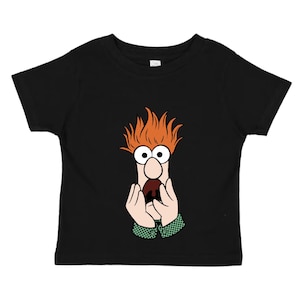 May include: Black toddler t-shirt featuring a cartoon graphic of Beaker from The Muppets. The graphic shows Beaker's face with orange hair, large glasses, and hands. The shirt has a crew neck and short sleeves.