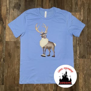 May include: A light blue t-shirt with a cartoon image of Sven the reindeer from the movie Frozen. The reindeer is brown and white and has antlers. The t-shirt has the text "Core Memory Designs" in a circle on the bottom right corner.