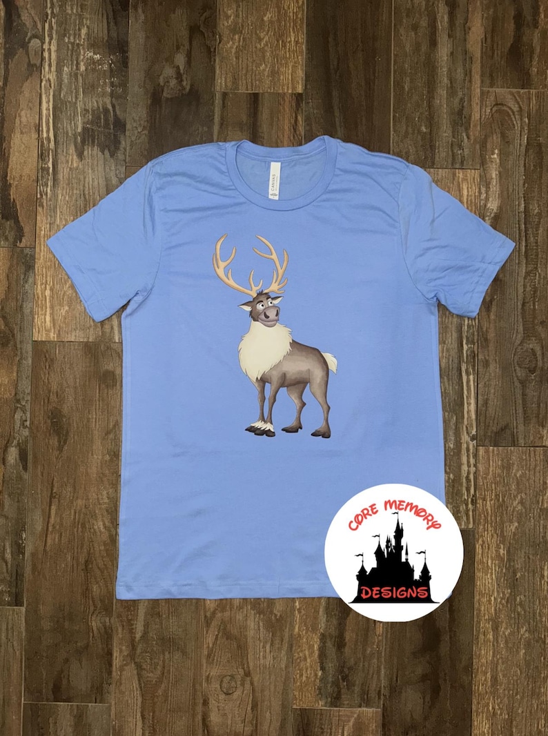 May include: A light blue t-shirt with a cartoon image of Sven the reindeer from the movie Frozen. The reindeer is brown and white and has antlers. The t-shirt has the text "Core Memory Designs" in a circle on the bottom right corner.