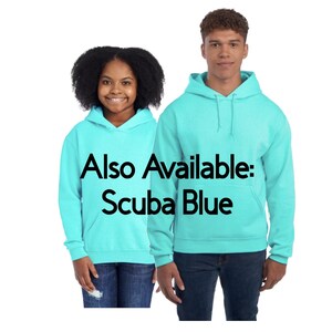May include: Two people wearing matching Scuba Blue hoodies with front pockets and drawstrings. The text "Also Available: Scuba Blue" is printed on the front of the hoodies. The hoodies are paired with blue jeans.