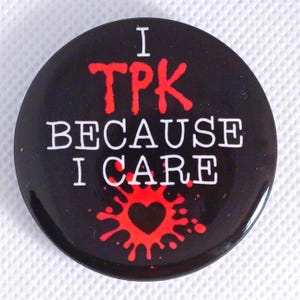 Puede incluir: Botón negro con texto blanco que dice "I TPK because I care" y un corazón rojo con salpicaduras de sangre.