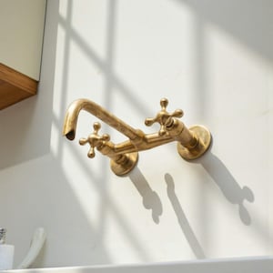 Peut inclure: Un robinet en laiton de style vintage avec des poignées en forme de croix est monté sur un mur blanc. Le robinet a un bec courbé et deux poignées séparées pour l'eau chaude et froide. Le robinet est conçu pour un évier ou un lavabo.