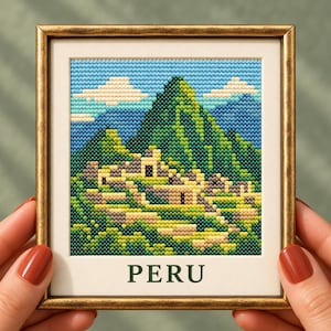 Puede incluir: Un bordado en punto de cruz enmarcado que representa las ruinas de Machu Picchu en Perú, con montañas verdes, estructuras de piedra y un cielo azul con nubes blancas. La palabra PERU está impresa en letras mayúsculas de color verde oscuro.