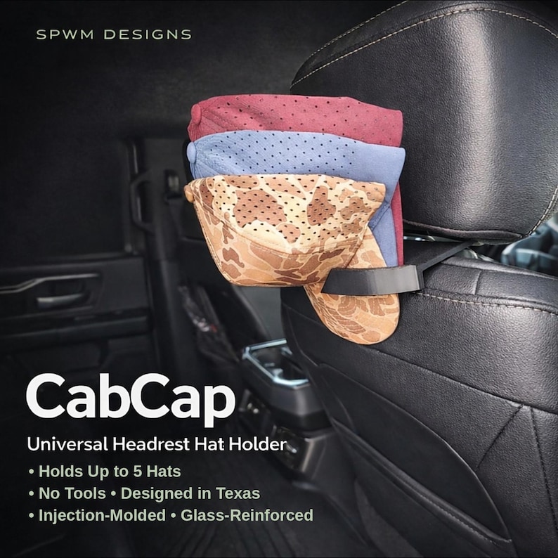 May include: A black plastic CabCap universal headrest hat holder attached to a vehicle seat headrest. The holder supports three stacked baseball caps in maroon, blue, and tan camouflage patterns. Text on the image includes SPWM DESIGNS, CabCap, and Universal Headrest Hat Holder, noting it holds up to 5 hats, requires no tools, is designed in Texas, and is injection-molded and glass-reinforced.