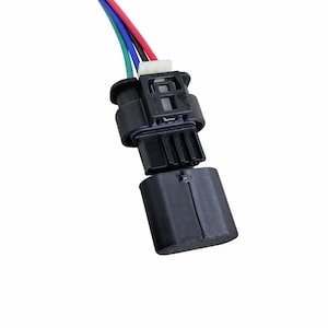 May include: Black electrical connector with multiple colored wires: red, blue, green, and black. The connector has a rectangular shape with a detachable cover. The wires are connected to the connector.