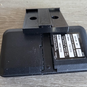 May include: Black garage door opener with a model number of 893LM MC and a date of 12/22. The opener is made by Chamberlain Group Inc. and has an FCC ID of HBW7359. The country of origin is Mexico.